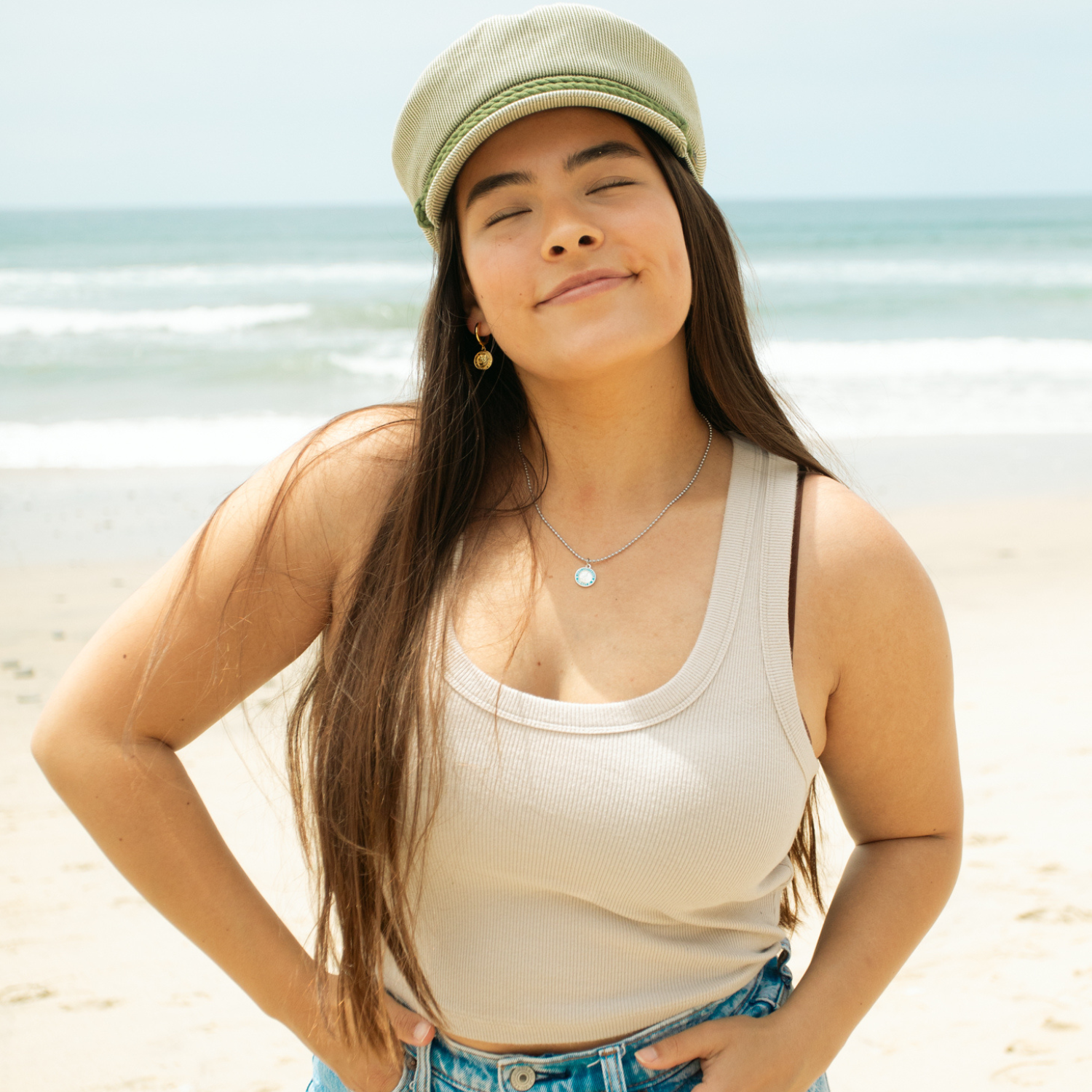 model wearing small silver baby blue st. christopher on beach